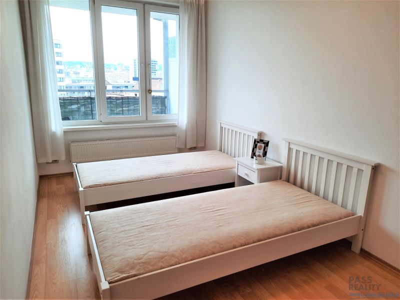 A bedroom with two beds, a nightstand, and a wooden decor floor in a two-room apartment.