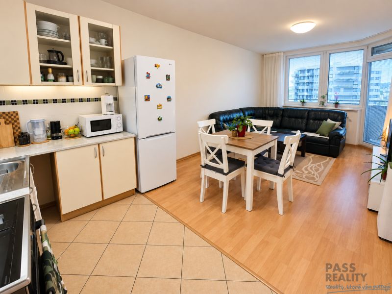 Kitchen and living room in a 2-room apartment with a wooden decor floor, dining table, and sofa.