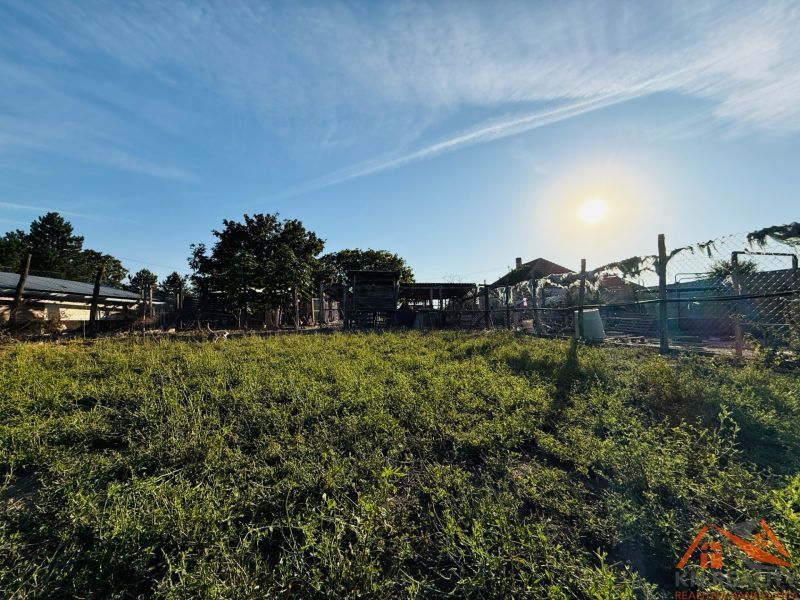 A family house in Komárno, surrounded by a fenced yard with greenery and buildings.