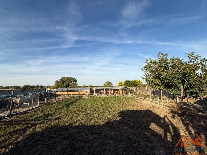 The exterior of a family house in Komárno with a fenced garden and a blue sky.