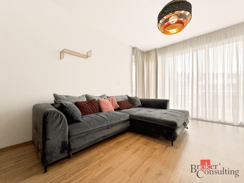 Living room in a two-room apartment with a corner sofa and a wooden decor floor.