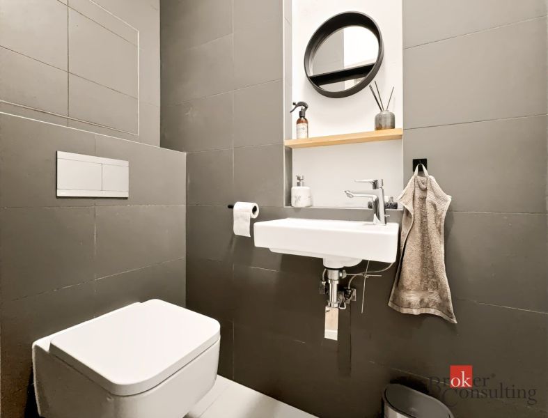 Compact bathroom in a 2-room apartment with a sink, mirror, and toilet.