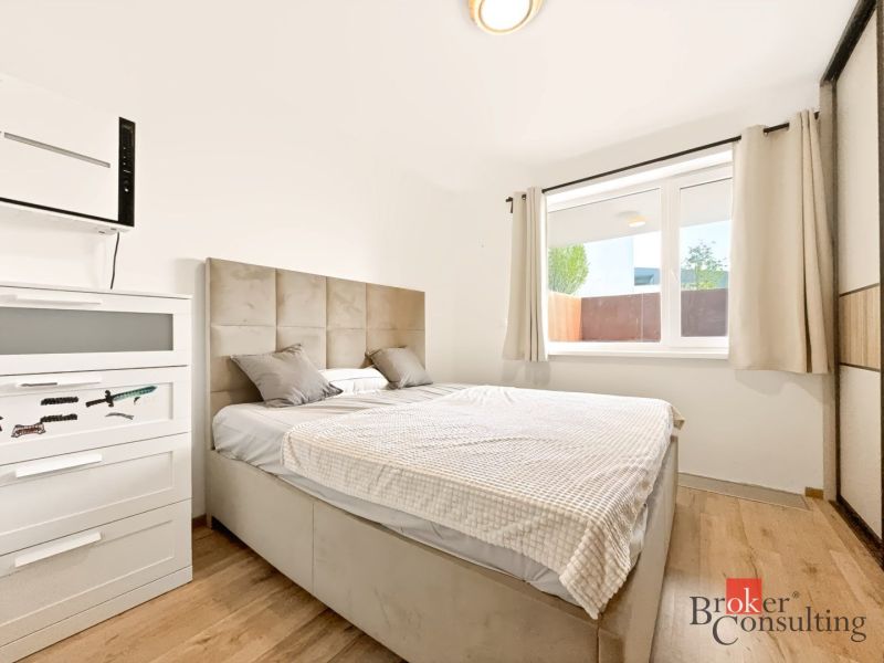 Bedroom in a 2-room apartment with a bed and a wardrobe, floor with wooden decor.