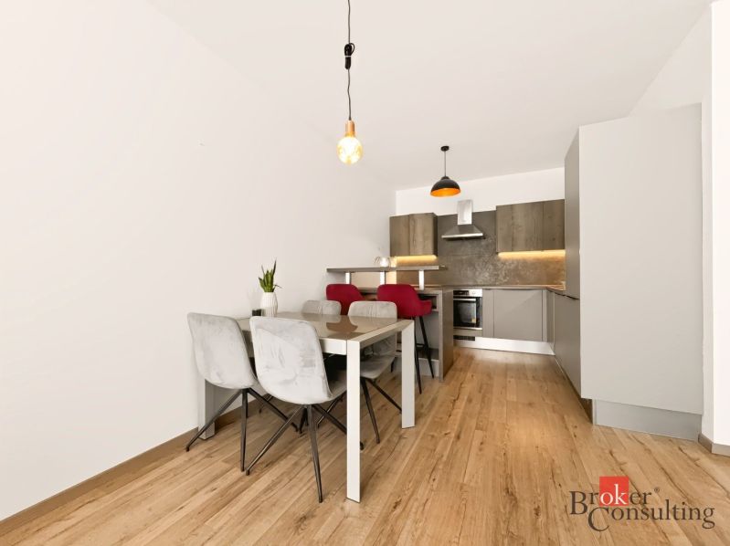 A kitchen in a 2-room apartment with a dining table and a floor with a wooden decor.