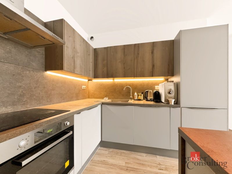 A kitchen with a corner unit, equipped with appliances, and a floor with a wood decor.