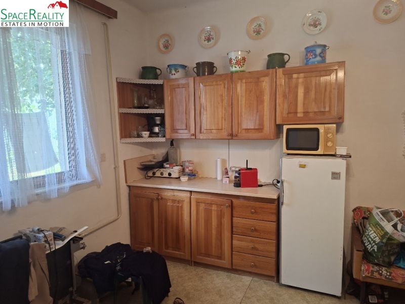 Kitchen with wooden cabinets, microwave, and refrigerator, Land - housing.