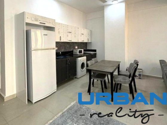 A kitchen in a 2-room apartment with a dining table, refrigerator, and washing machine.