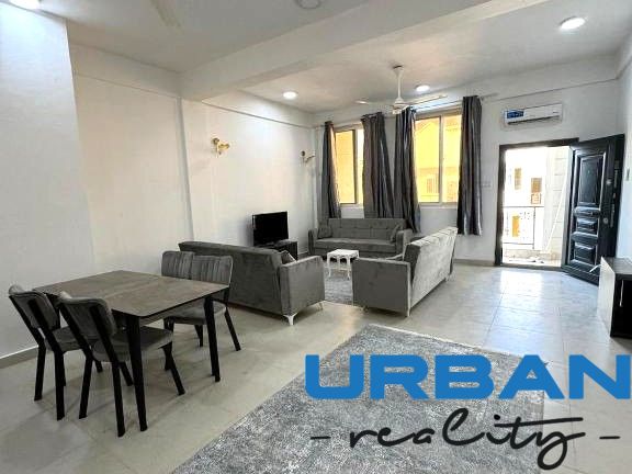 2-room apartment with dark sofas, a dining table, and a television, with a wooden decor floor.