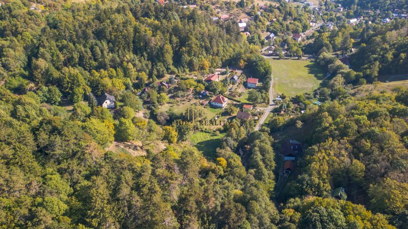 Aerial view of green recreational plots in Štiavnické Bane with house roofs.
