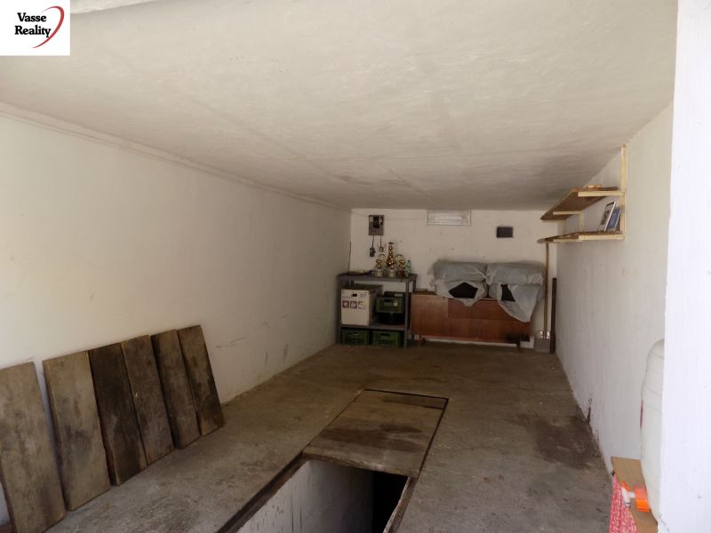 Garage with shelves, road floor, racks, and stored items.