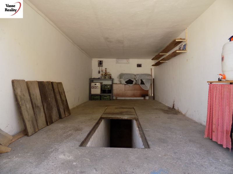 Garages with a maintenance pit and storage spaces with shelves and wooden surfaces.