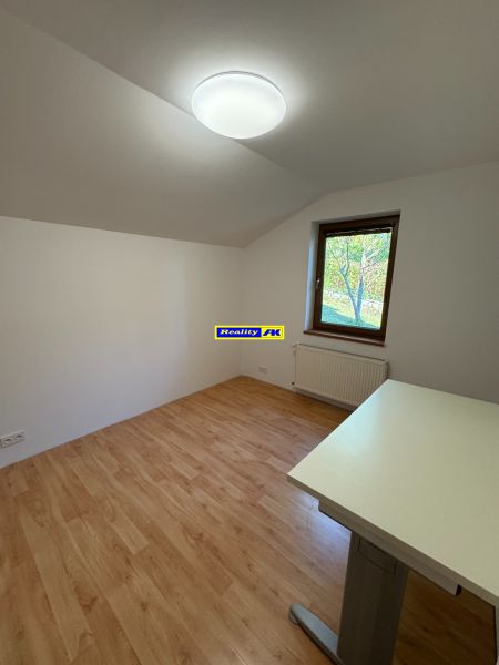 A room with a wooden decor floor, a table, and a window in a family house.
