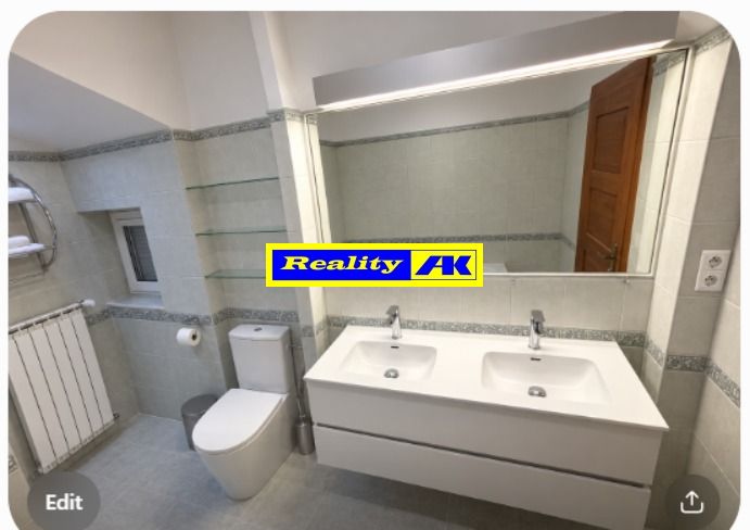 Bathroom in a family house with a double sink, toilet, and mirror.