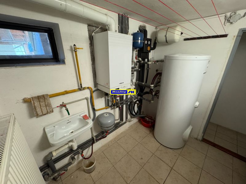 Technical room with a radiator, sink, and boiler in a family house.