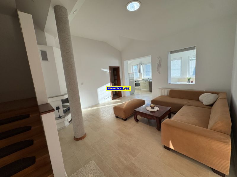 Living room in a family house with a beige sofa and access to the kitchen.