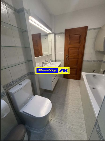 Bathroom with a bathtub and toilet in a family house, white tiles and wooden doors.