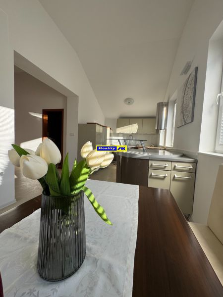 A kitchen in a family house with a decorative vase and white flowers on the table.