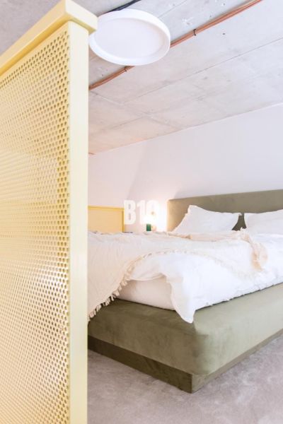 A bedroom in a two-room apartment with a bed and a yellow partition.