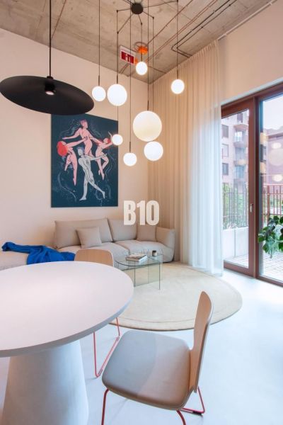Living area with white furniture, a round table, and art in a 2-room apartment.