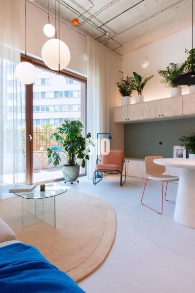 A bright interior of a 2-room apartment with round lights, plants, and a glass table.