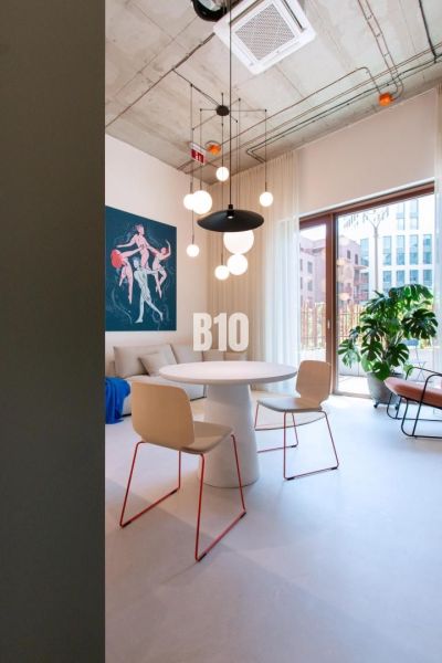 Dining area in a 2-room apartment with an art painting and pendant lights.