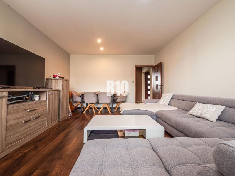 A comfortable living room with a gray sofa and a wooden decor floor in a 3-room apartment.