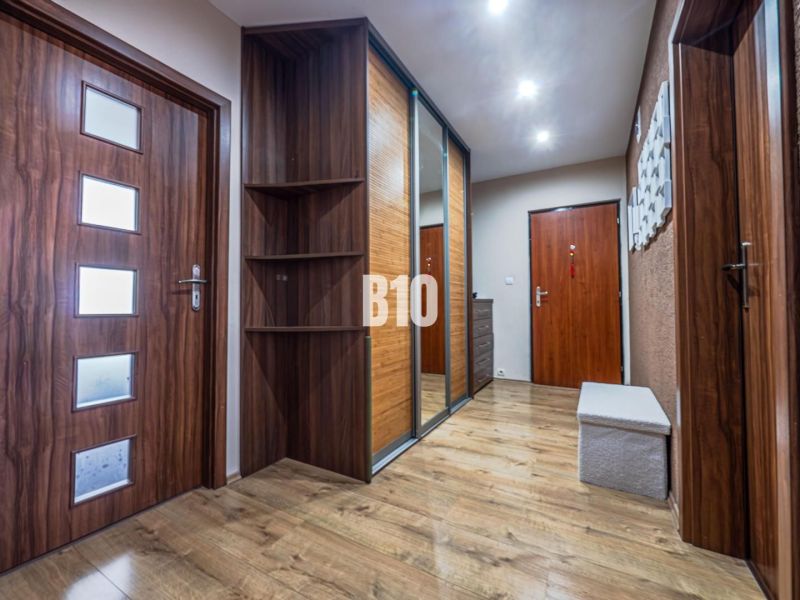 A hallway in a 3-room apartment with a wooden decor floor and a built-in wardrobe.