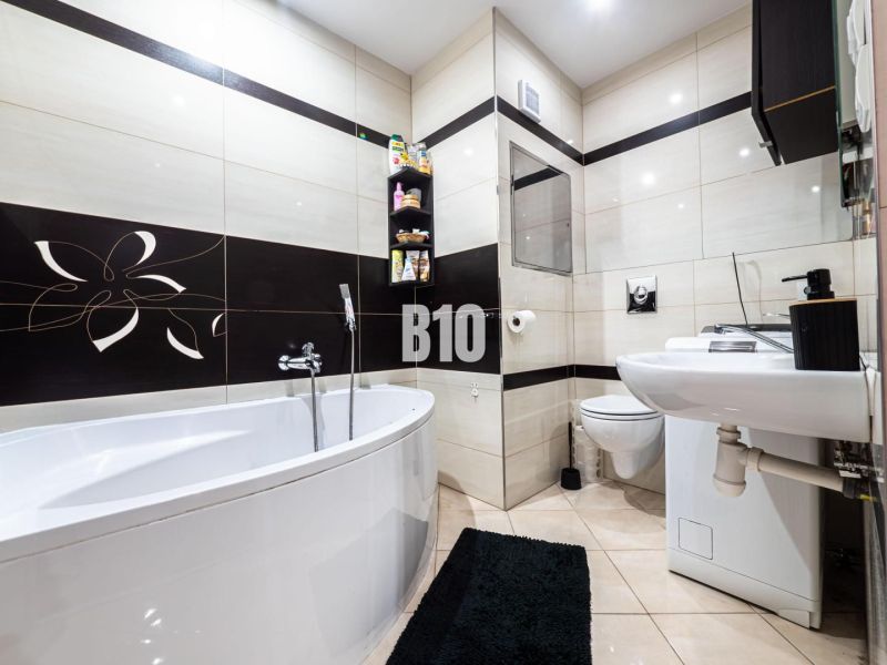 Bathroom in a 3-room apartment with a bathtub, toilet, and black-and-white decor.
