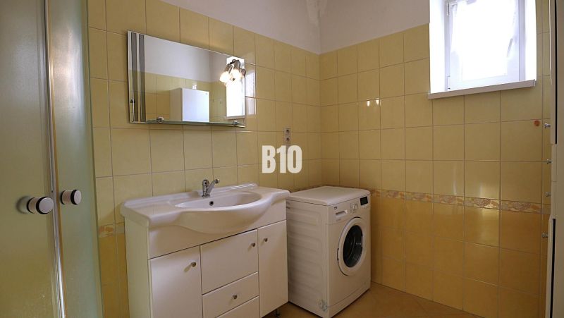 A bathroom in a family house with a washing machine and yellow tiles.