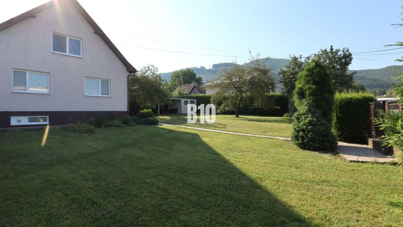 A family house in Žilina with a well-maintained garden and a view of the surrounding hills.
