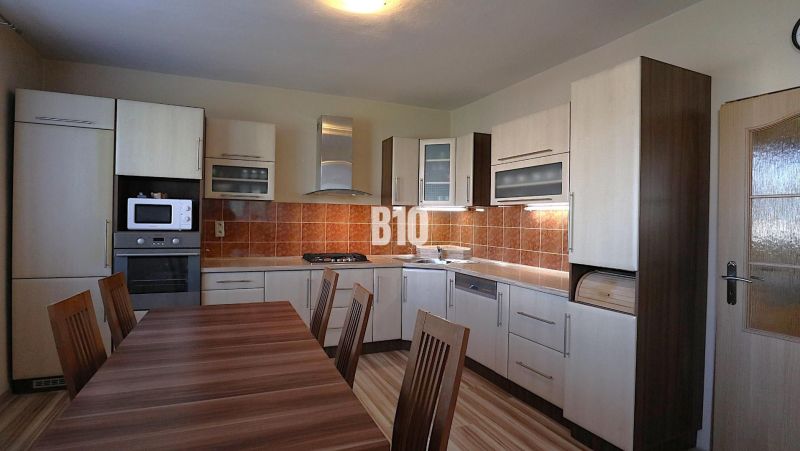 A kitchen in a family house with wooden decor and appliances, featuring a spacious dining table.