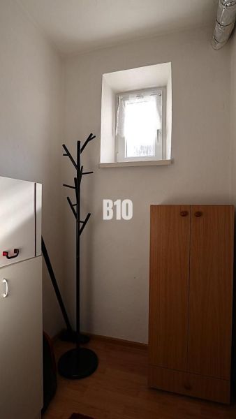 A small room in a family house with a coat rack and a wardrobe, floor with wooden decor.