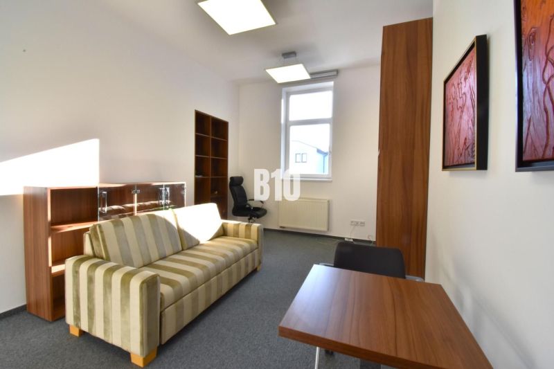 Office with a striped sofa, desk, and shelf, simple interior.