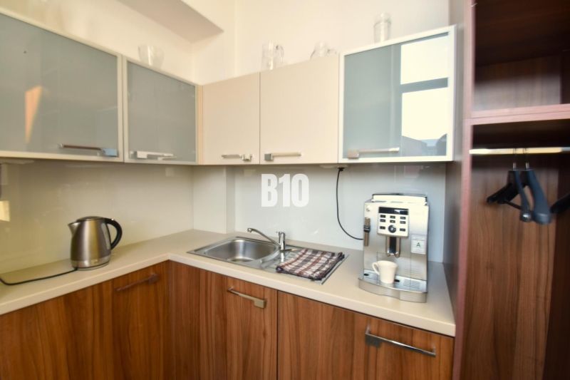 A kitchenette with a coffee maker and an electric kettle in an office with wooden decor.