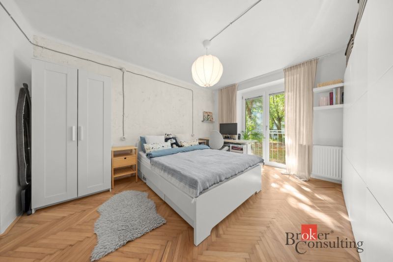 A bedroom with a bed, furniture, and flooring with a wood decor in a 2-room apartment.