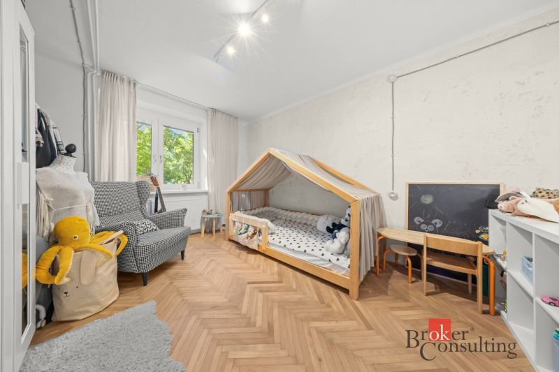 Children's room with a wooden decor floor, a house-shaped bed, and an armchair.