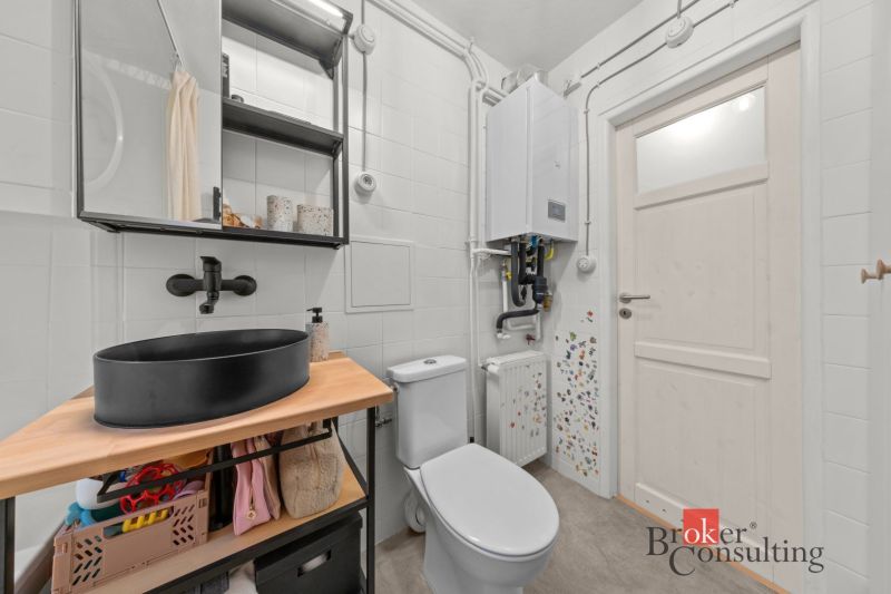 Bathroom in a 2-room apartment with a black sink and a boiler on the wall.