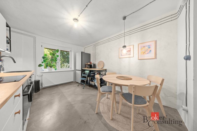 A kitchen in a 2-room apartment with a window, a dining table, and a floor with a wooden decor.
