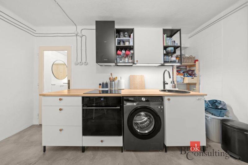 A kitchen in a 2-room apartment with a washing machine and a wooden decor countertop.