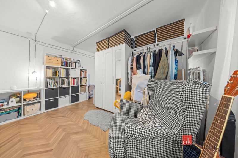 Interior with shelves, clothing, and a chair in a 2-room apartment; floor with wood decor.