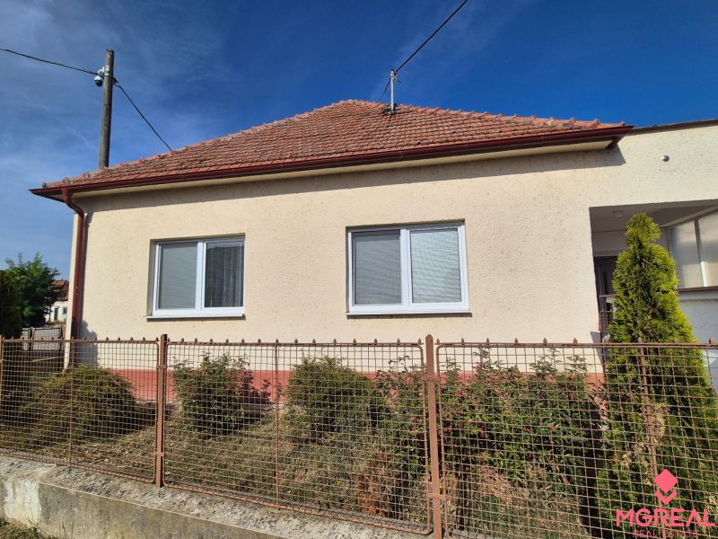 A family house in Ludanice with a white facade and a red roof, fenced garden.
