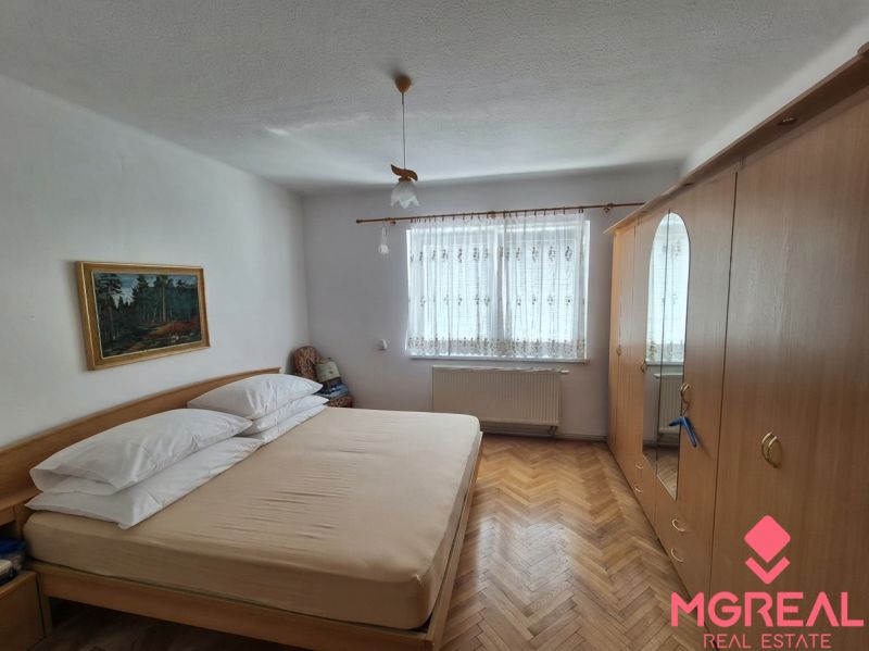 A bedroom in a family house with a wooden decor floor, wardrobes, and a painting.