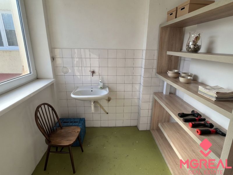 Bathroom in a family house with a sink, chair, and shelving system.