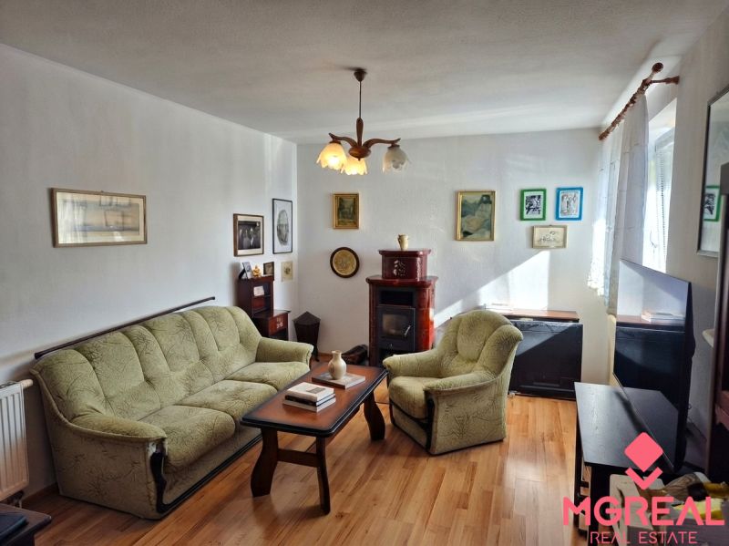 Living room in a family house with a sofa and an armchair, floor with wooden decor.
