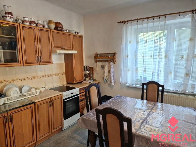 A kitchen in a family house with wooden decor, a kitchen unit, a dining table, and decorations.