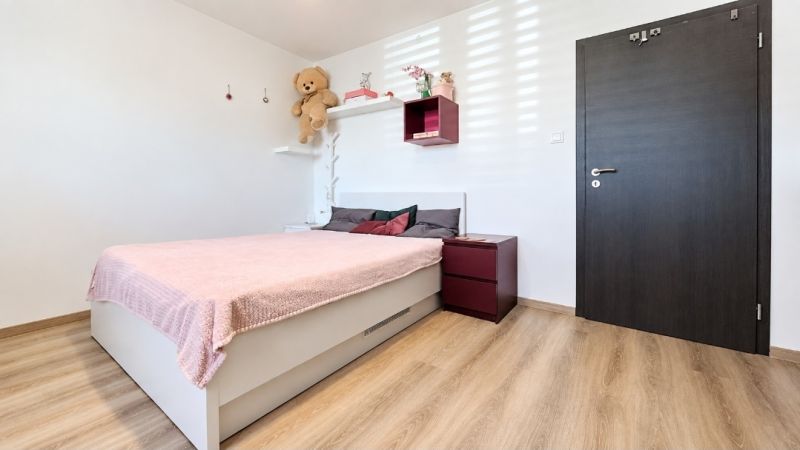 A bedroom in a family house with a pink bed and a wooden decor floor.