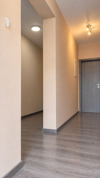 A hallway in a family house with a wooden decor floor and neutral walls.