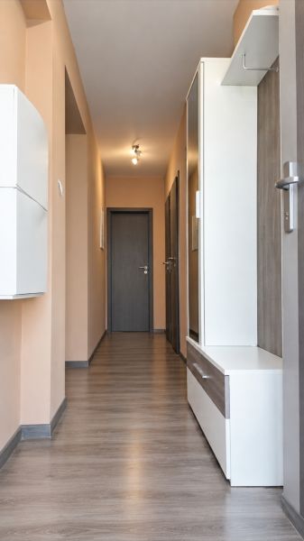 A hallway in a family house with a wooden decor floor and light-colored walls.