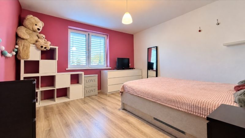 Children's room with a crib, wardrobe, toys, and a floor with a wooden decor in a family house.