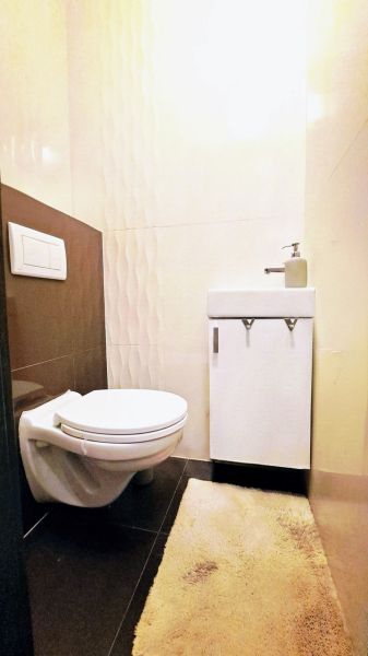 A bathroom in a family house with a toilet, a sink, and embossed tiles.